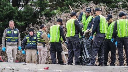 GBI agents search diligently through the brush on Candler Road on Wednesday after an officer-involved shooting Tuesday night, blocks away from a December shooting that killed another DeKalb officer.