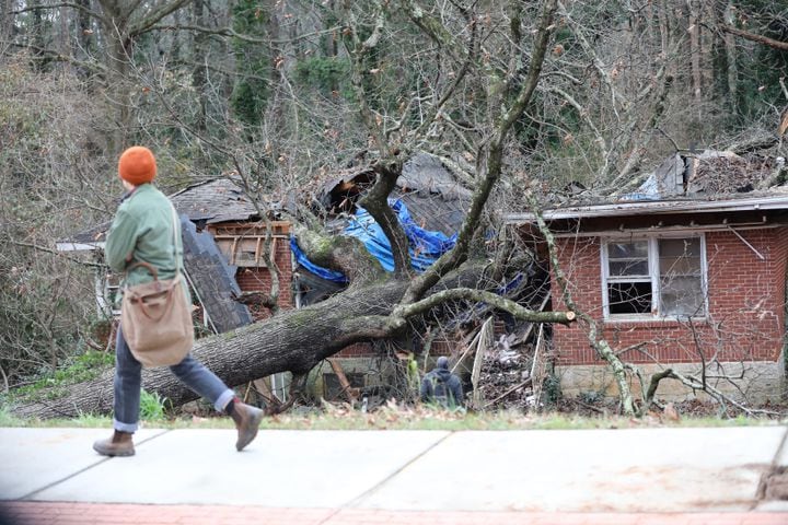 A person walks in the front of the house where a tree fell in early hours in Dekalb County, killing a 5-year-old boy and sending his mother to the hospital. Monday, January 3, 2022. Miguel Martinez for The Atlanta Journal-Constitution