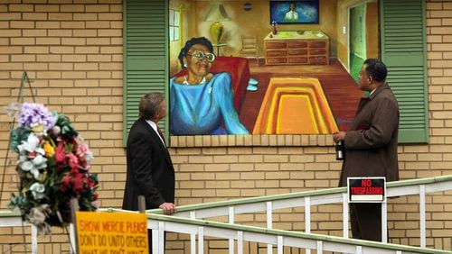 Buckhead businessman John Gordon, left, and the Rev. Anthony Motley of Lindsay Street Baptist Church, look at a Janssen Robinson mural of Kathryn Johnson painted on plywood over her boarded-up home in the English Avenue community in November 2008. The two men are working to improve the quality of life in the community following the police shooting of the 92-year-old Johnston. CURTIS COMPTON / AJC file