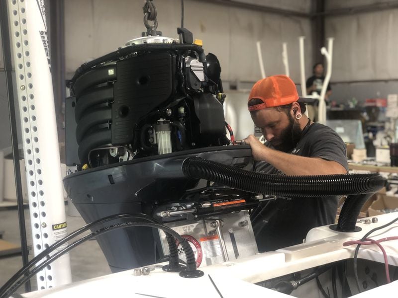 Charlie Dieringer hangs a motor on a new boat at Composite Research in Blackshear. The company builds Sea Born, Spyder and Sundance boats, and owner Wally Bell says Chinese tariffs are affecting Georgia’s robust boat-building industry, which directly employs about 10,000 workers. Courtesy of Composite Research.