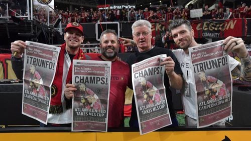 Atlanta United fans hold The Atlanta Journal-Constitution special edition after the team beat the Portland Timbers during MLS championship on Saturday, December 8, 2018, at Merceds-Benz Stadium. (Photo: HYOSUB SHIN / HSHIN@AJC.COM)