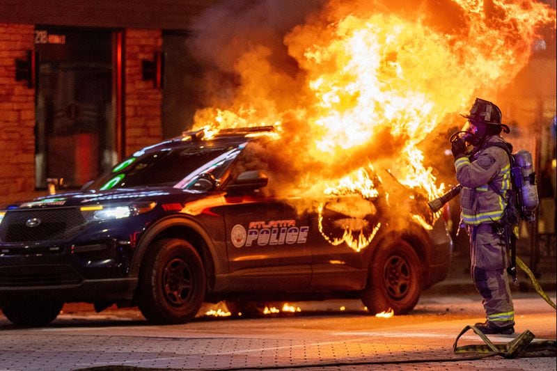 Atlanta firefighters prepared to extinguish a police car that was set afire during a protest in Atlanta on Jan 21, 2023. The Atlanta Police Department said several arrests had been made. (Steve Schaefer/The Atlanta Journal-Constitution/TNS)