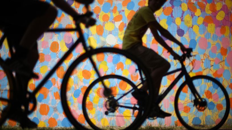 Bicyclists cruise along the Beltline past a mural by HENSE under Virginia Avenue. (Ben Gray / bgray@ajc.com)