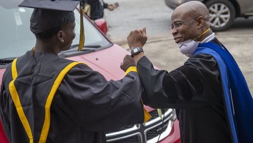 Frederick Douglass High School principal Ellis Duncan (right) congratulates a graduating senior with an elbow bump during a drive-thru celebration event at the school in Atlanta's Center Hill community, May 20, 2020. (ALYSSA POINTER / ALYSSA.POINTER@AJC.COM)