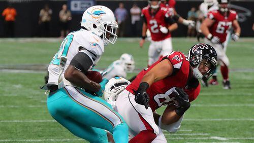 Miami Dolphins cornerback Cordrea Tankersley, center, hits Atlanta Falcons tight end Austin Hooper, right, knocking the ball loose for an interception by Dolphins' safety Reshad Jones, left, during the final minute ofan NFL football game Sunday, Oct. 15, 2017, in Atlanta.(Curtis Compton/Atlanta Journal-Constitution via AP)