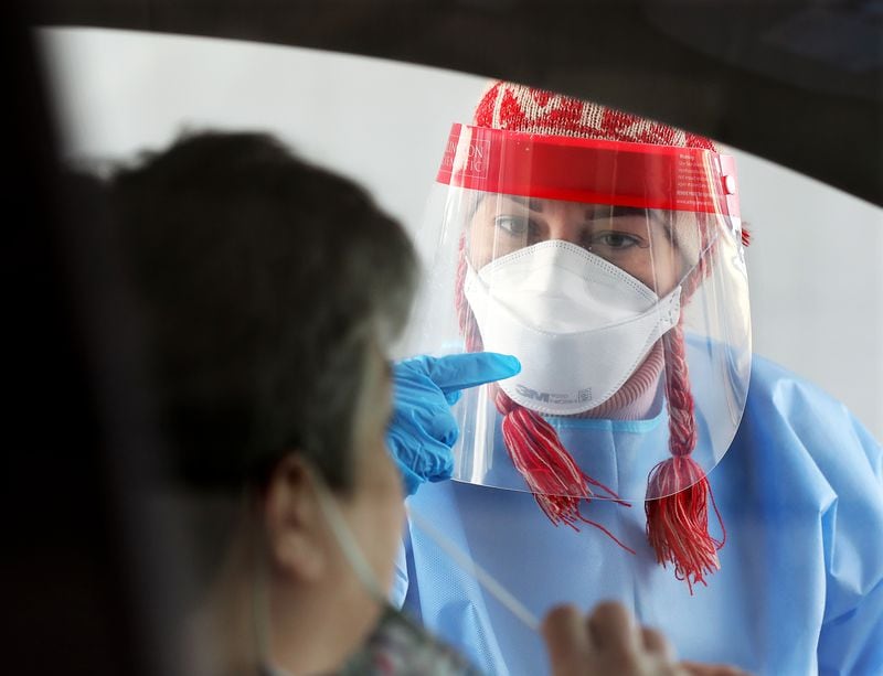 122320 Doraville: RN Elham Roshanraun talks a motorist through how to perform a self swab at a free drive through COVID-19 DeKalb Board of Health testing site located by the Brandsmart USA on Wednesday, Dec. 23, 2020, in Doraville.  “Curtis Compton / Curtis.Compton@ajc.com”