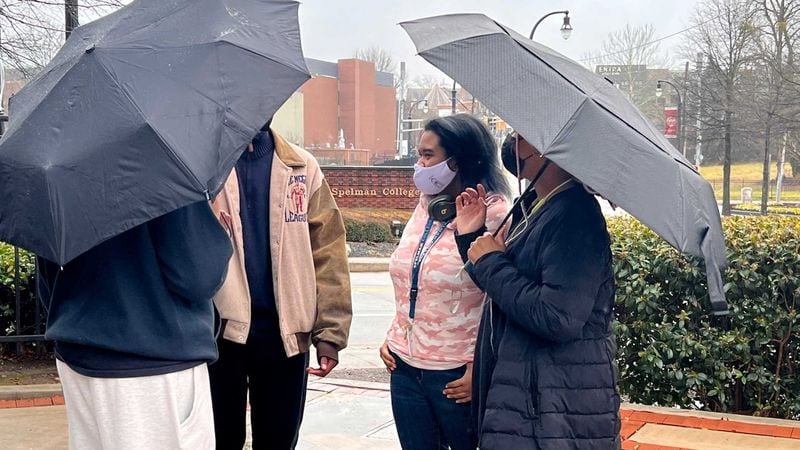 Spelman College student Lindsey Fiesta, dressed in pink under the umbrella, talks with some of her friends on campus on Thursday, Feb. 3, 2022. Fiesta, 18, said the recent bomb threats have been scary, but she's pressing on with her studies. (Eric Stirgus / Eric.Stirgus@ajc.com)
