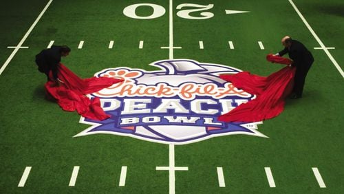 College Football Hall of Fame CEO Dennis Adamovich (left) and Peach Bowl Inc. CEO Gary Stokan unveil a Chick-fil-A Peach Bowl logo on the Hall of Fame’s indoor playing field.