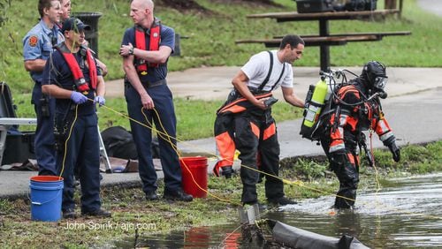 DeKalb County fire and rescue dive members work to pull a car out of McAfee Park Lake in Decatur. The car went in the lake Wednesday, but officials are not yet sure how it got in there.  JOHN SPINK/JSPINK@AJC.COM