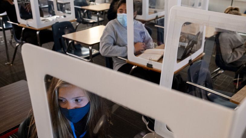 201105-Marietta-Celeste Martin, left, and Monserrath Guerrero look to their teacher from behind plastic partitions during their language arts class at Marietta Middle School on Thursday afternoon, Nov. 5, 2020. Even though there are only five students in the room during class, they all wear masks and sit behind plastic partitions. Ben Gray for the Atlanta Journal-Constitution