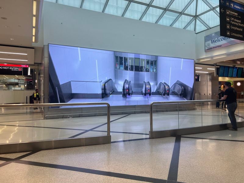 A screen now shows a video of the top of the escalators at Hartsfield-Jackson International Airport's west crossover.