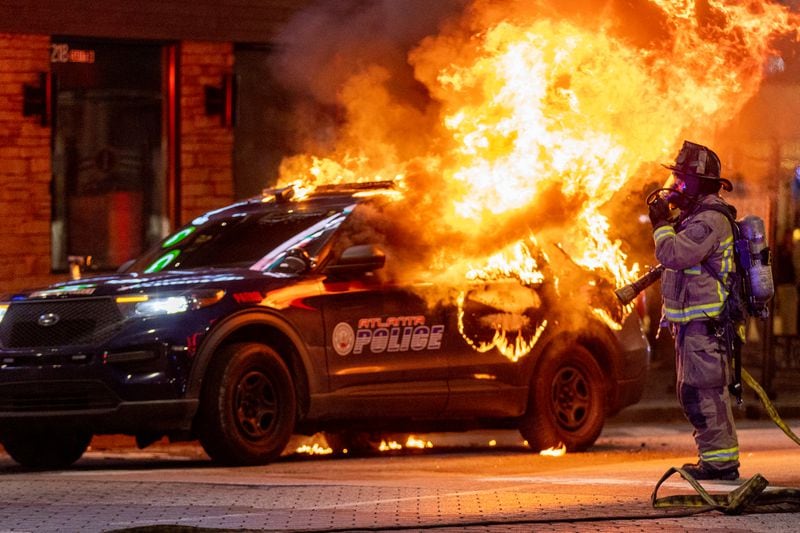 Atlanta firefighters prepared to extinguish a police car that was set afire during a Forest Defenders protest in Atlanta Saturday, Jan 21, 2023. The Atlanta Police Department said several arrests had been made. (Photo: Steve Schaefer / steve.schaefer@ajc.com)