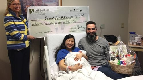 Jennifer Herring presents Anna and Mike McDermott with a check for $1,529 for Coen, the first “Tax Day Baby” born at Northside Hospital in 2018.