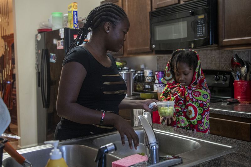 10/12/2020 - Hampton, Georgia - Mapillar Dahn gives her daughter Hajar Tyler, 11, a snack during her virtual learning at Eddie White Academy at their residence in Hampton, Monday, October 12, 2020.  (Alyssa Pointer / Alyssa.Pointer@ajc.com)