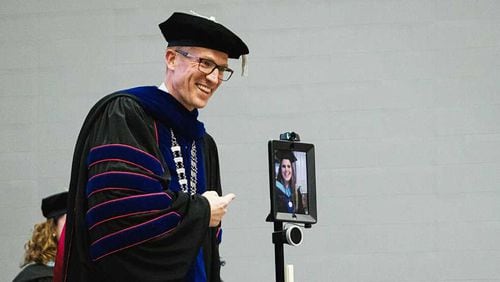 University of West Georgia President Brendan Kelly (left) smiles as he gives a degree virtually to Samantha Conerly, who was unable to attend the ceremony because she is pregnant and on bed rest. The school and Conerly directed a robot with a camera and iPad to talk to Kelly. (Courtesy of University of West Georgia)