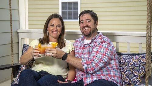 Heather and Kevin Freaney have been creating cocktails on an almost nightly basis since the COVID-19 pandemic has affected their lives. They are holding a Malibu Sunset cocktail. (ALYSSA POINTER / ALYSSA.POINTER@AJC.COM)