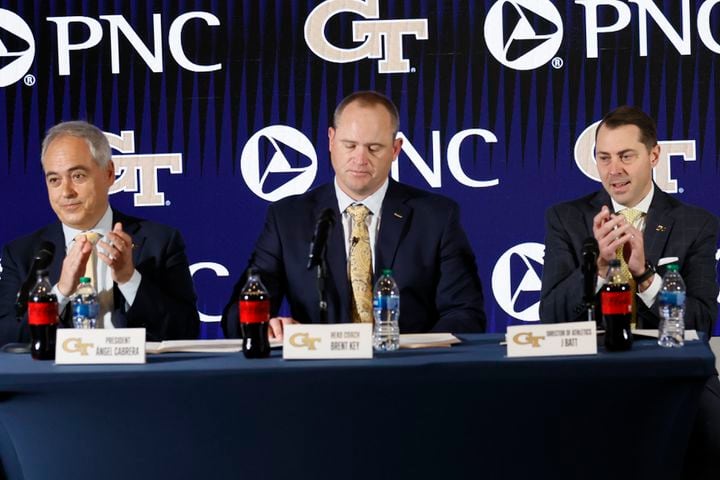 Georgia Tech President Ángel Cabrera (left) and athletic director J Batt (right) applaud as they introduce the new football head football coach Brent Key during a news conference on Monday, Dec. 5, 2022.
 Miguel Martinez / miguel.martinezjimenez@ajc.com