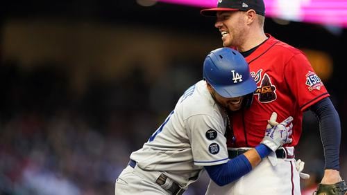 Atlanta Braves' Freddie Freeman, top, greets Los Angeles Dodgers' Mookie Betts, bottom, at first base in the fourth inning of a baseball game Friday, June 4, 2021, in Atlanta. (AP Photo/Brynn Anderson)