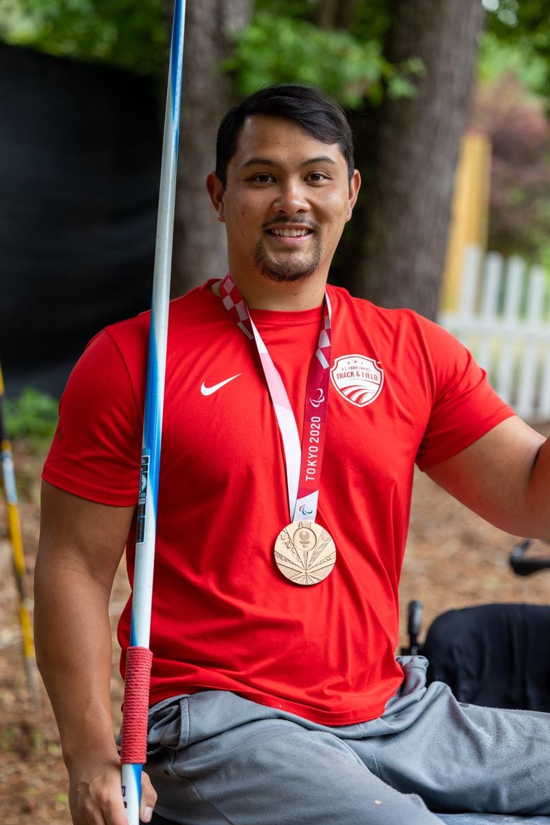 Portrait of American Paralympic Medalist Justin Phongsavanh with his bronze medal at his McDonough home. He was paralyzed from the chest down after being shot in a parking lot in 2015. He competed for Team USA at the 2020 Tokyo Paralympics and earned the bronze in javelin & continues to train for future paralympics. PHIL SKINNER FOR THE ATLANTA JOURNAL-CONSTITUTION