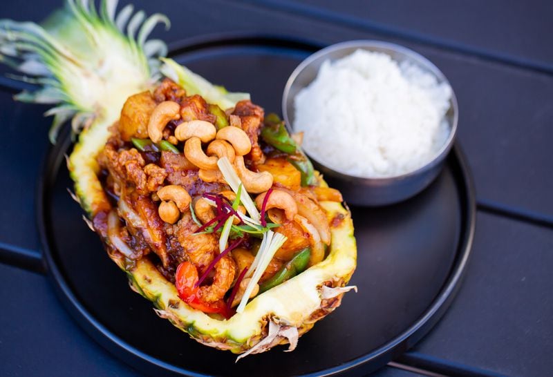 A medley of stir-fried, crispy chicken, veggies and pineapple is presented in a hollowed pineapple half for 26 Thai Kitchen & Bar's pineapple boat. Ryan Fleisher for The Atlanta Journal-Constitution