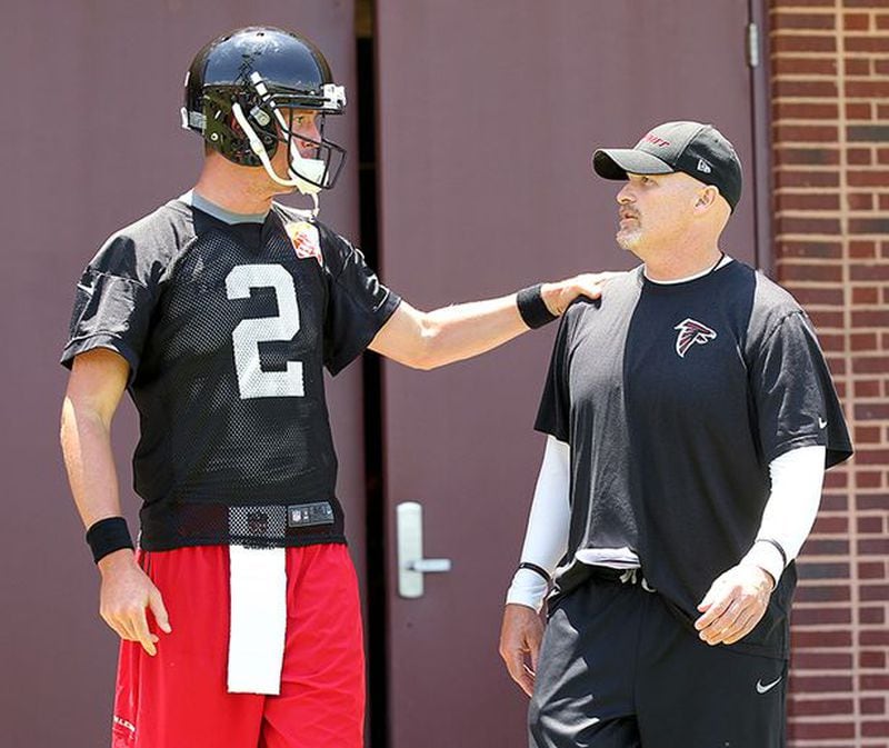 Falcons quarterback Matt Ryan and head coach Dan Quinn confer as they take the field for team practice on the second day of a three-day mini-camp Wednesday, June 17, 2015, in Flowery Branch. (Curtis Compton/AJC)