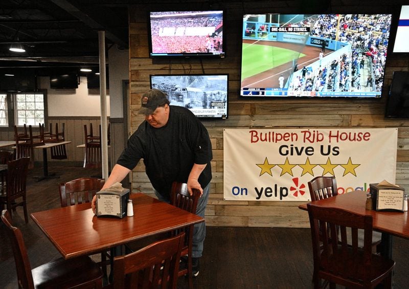 Kevin Gunter, general manager, cleans tables after lunch customers left Bullpen Rib House near the Center Parc Stadium in Atlanta on Tuesday. Last weekend's first football game gave the business a good bump, and Gunter is hoping for more. (Hyosub Shin / Hyosub.Shin@ajc.com)