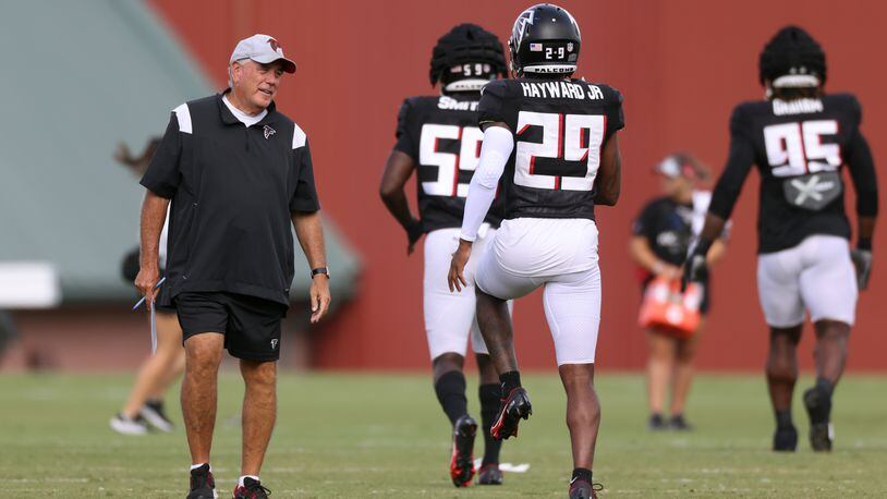 Falcons defensive coordinator Dean Pees (left) talks with cornerback Casey Hayward during training camp. Pees will direct a massive change of personnel in his second year with the Falcons. (Jason Getz / Jason.Getz@ajc.com)