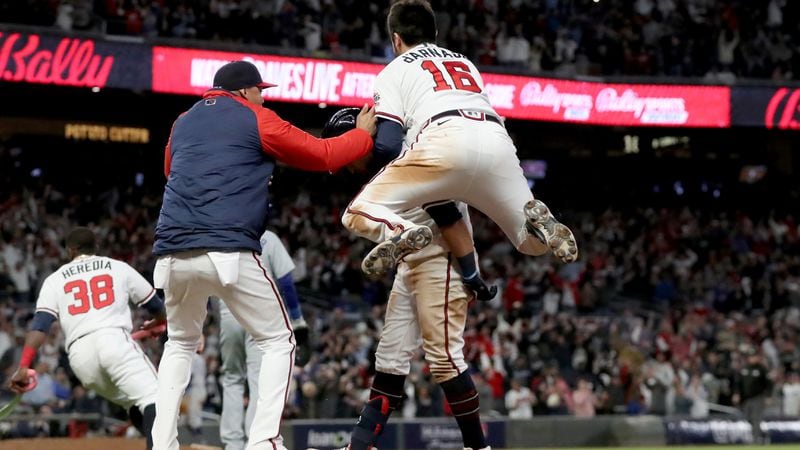 Braves catcher Travis d'Arnaud (16) jumps onto leftfielder Eddie Rosario after Rosario made the game-winning hit that scored shortstop Dansby Swanson in the ninth inning of Game 2 of the NLCS Sunday, Oct. 17, 2021, at Truist Park in Atlanta. (Curtis Compton / curtis.compton@ajc.com)