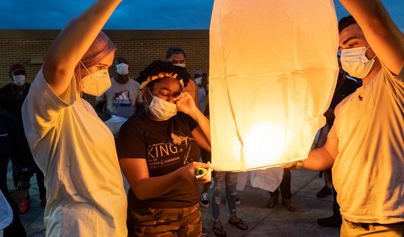 Amber Gregory, center, wipes away a tear while helping launch a sky lantern in honor of her brother Kyle Gregory. (Ben Gray for the Atlanta Journal-Constitution)