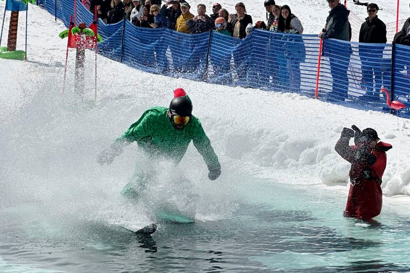 A skier participates in a pond skimming event at Gunstock Mountain Resort, Sunday, April 7, 2024, in Gilford, N.H. The wacky spring tradition is happening this month at ski resorts across the country and is often held to celebrate the last day of the skiing season. (AP Photo/Nick Perry)