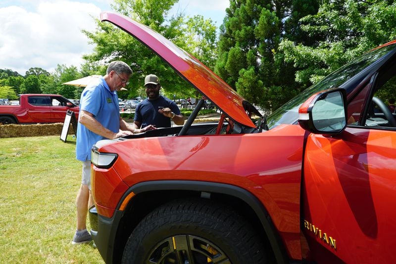 Bill Dobbs, who serves on the board of the Newton County Industrial Development Authority, looks under the hood of a Rivian R1T with Rivian's Charles Alexander at a community appreciation event hosted by the company on Saturday, May 14, 2022. (Drew Kann / Drew Kann@ajc.com)