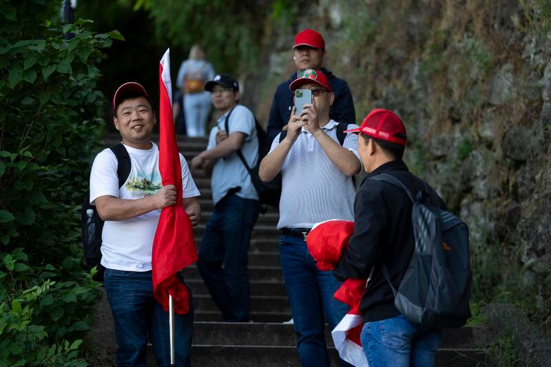 Chinese nationals take pictures of Tibetan protesters during Xi Jinping's visit to Budapest, Hungary, on Thursday, May 9, 2024. Many Chinese nationals claiming to be volunteers with China's embassy are present in the city, wearing red baseball caps to identify themselves. (AP Photo/Denes Erdos)