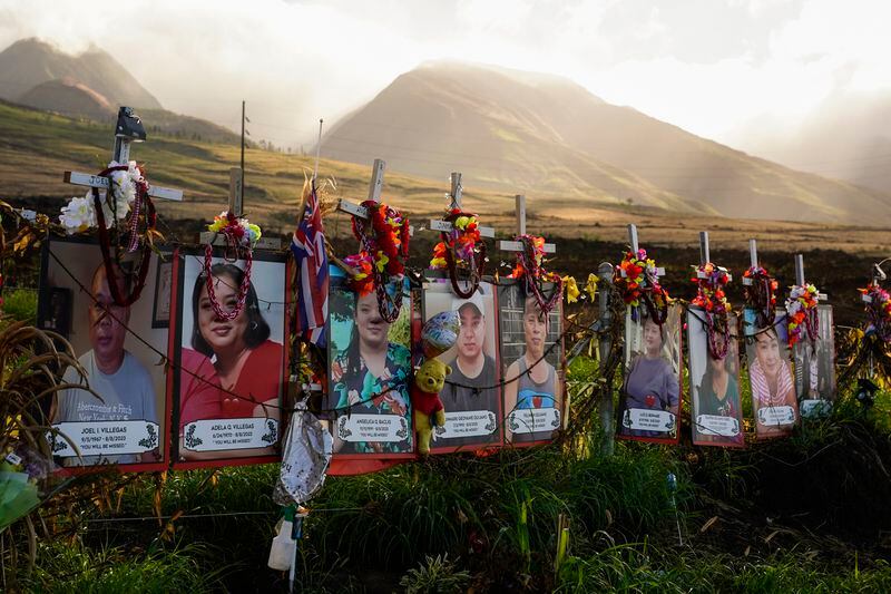 FILE - Photos of victims are displayed under white crosses at a memorial for the August 2023 wildfire victims, above the Lahaina Bypass highway, Dec. 6, 2023, in Lahaina, Hawaii. The Maui Fire Department is expected to release a report Tuesday, April 16, 2024, detailing how the agency responded to a series of wildfires that burned on the island during a windstorm last August. (AP Photo/Lindsey Wasson, File)