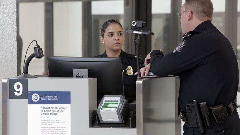 Two agents of U.S. Customs and Border Protection talk on Feb 27, 2018 while waiting for passengers to arrive at one of the facial recognition stations now operating at Miami International Airport. (Jose A. Iglesias/Miami Herald/TNS)