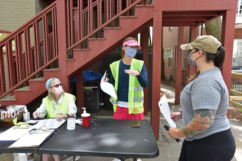 Volunteers Jodi Lewis Lipsitz (left) and Stefanie Agusta, help Emily Borcuta (right) with checking in for COVID-19 vaccination at the parking lot at Highland Urgent Care & Family Medicine in Atlanta on Thursday.(Hyosub Shin / Hyosub.Shin@ajc.com)