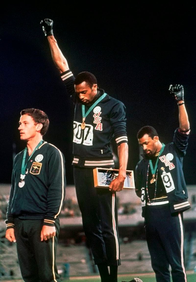 Sprinters Tommie Smith, center, and John Carlos raise their fists in a protest seen around the world during the playing of national anthem after Smith received the gold and Carlos the bronze for the 200-meter run at the 1968 Summer Olympic Games in Mexico City. Australian silver medalist Peter Norman is at left.  (AP Photo/File)