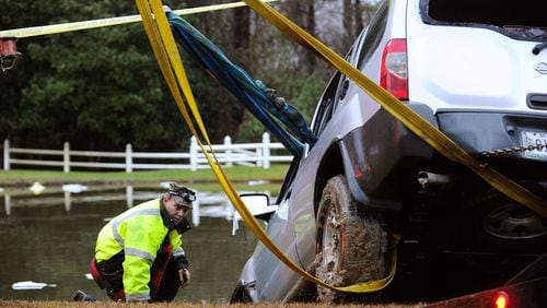 Officials help to remove an SUV that was submerged in a pond off Batesville Road in rural Cherokee County after a driver was rescued by firefighters near Atlanta National Golf Course early Monday morning, Dec. 29, 2014, in Canton.