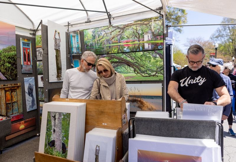 Rob and Julia Better, left, of Milton, look at Brian K Miller Photography prints on Sunday, April 10, 2022 at the 86th annual Atlanta Dogwood Festival in Piedmont Park. This year’s three-day festival had art of all shapes and sizes, jewelry, fare food and a kids village with arts and crafts, games and rides.  (Jenni Girtman for The Atlanta Journal-Constitution) 