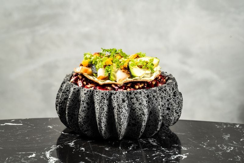 The hamachi tostada at Palo Santo is presented on top of a volcanic bowl filled with decorative raw heirloom corn. Courtesy of the Cocktail Shaker