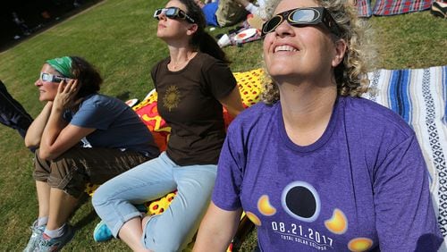 Robyn Diamond (from left), Sam Dressler, and Sherie Green, from Dunwoody, don special glasses to watch the total eclipse at Ramah Darom on Monday in Clayton, a city in the path of totality in North Georgia. Now there’s a way to help others view another eclipse by donating those glasses. Curtis Compton/ccompton@ajc.com