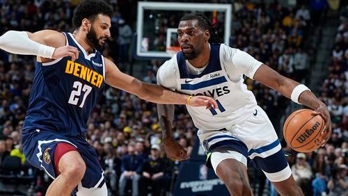 Minnesota Timberwolves center Naz Reid, right, drives against Denver Nuggets guard Jamal Murray during the second half of an NBA basketball game Wednesday, April 10, 2024, in Denver. (AP Photo/David Zalubowski)
