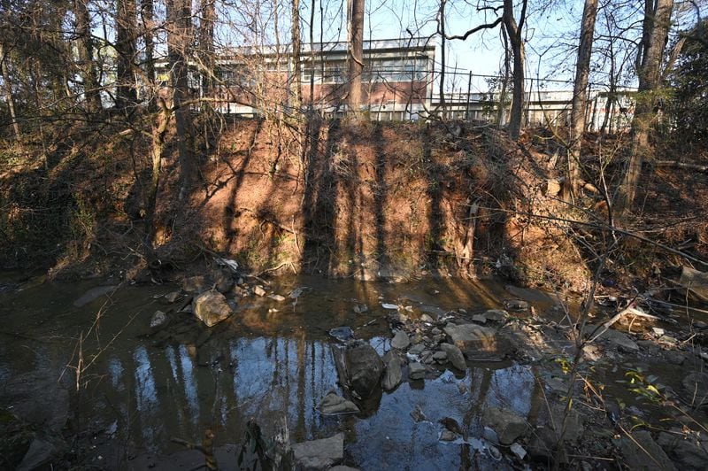 An unnamed tributary of the South River runs between TAV Holdings and the back of Crawford W. Long Middle School, seen here in the background. Samples from the school and the creek were collected by the EPA on Jan. 17, and the results of those tests will determine the next steps, according to EPA spokesperson Davina Marraccini. (Hyosub Shin / Hyosub.Shin@ajc.com)
