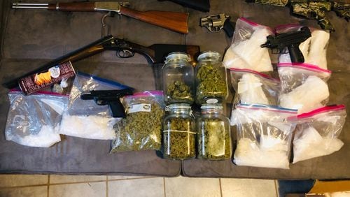 Multiple firearms and pounds of suspected drugs were seized in the raids on two suspected gang caches in Lawrenceville.