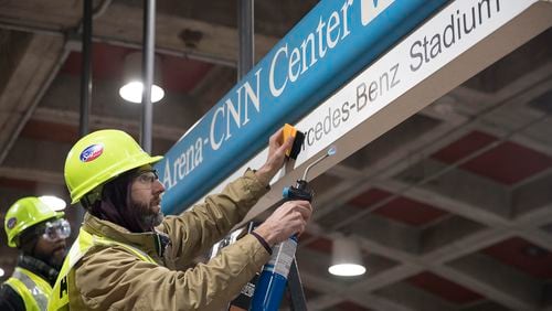 01/16/2019 -- Atlanta, Georgia -- Tim Carl (second from left) of Advantage Graphics & Signs uses a torch to gaurantee the cohesiveness of the new Mercedes-Benz signage at the  MARTA Dome/GWCC/Philips Arena/CNN Center Transit in Atlanta, Wednesday, January 16, 2019. Advantage Graphics & Signs worked in the transit station on Wednesday to replace signage that mislabeled Atlanta's two newly named sport stadiums. (ALYSSA POINTER/ALYSSA.POINTER@AJC.COM)