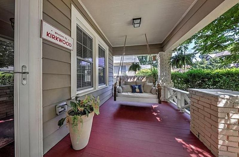 A red-floored porch with a swing creates welcoming curb appeal.