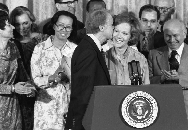 Jimmy Carter kisses Rosalynn Carter during ceremony in which he receives the Final Report of the President's Commission on Mental Health. April 27, 1978. (White House Staff Photographer / Jimmy Carter Library)