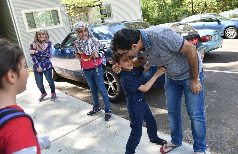 Yaser Musa kisses his son, Issa, 5, outside their Clarkston apartment as he waits for his other children (from left) Samar, 10, Nor Alhoda, 12, and Reem, 11, on April 13, 2017. HYOSUB SHIN / HSHIN@AJC.COM