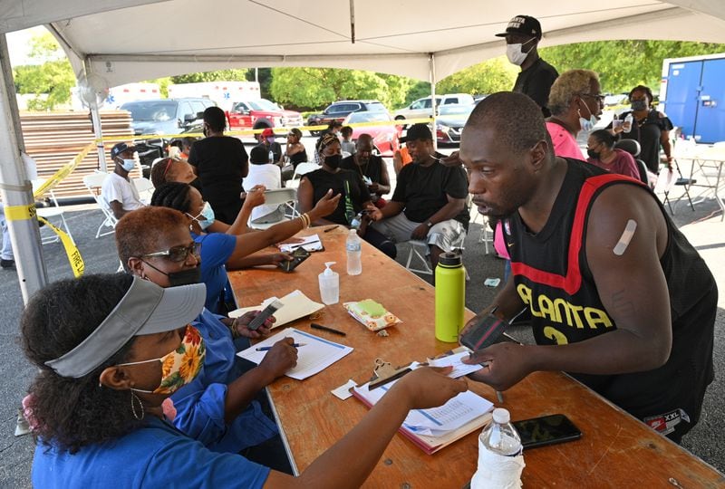 Kerwjuan Bailey (right) receives a $100 prepaid debit card from the DeKalb County BOard of Health's Audrey Moyer (left) after he got the COVID-19 vaccine shot during a vaccination event at The Gallery at South DeKalb in Decatur on Saturday, August 13, 2021. (Hyosub Shin / Hyosub.Shin@ajc.com)