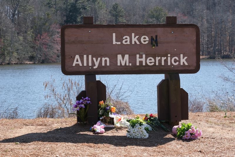 The sign for Lake Herrick has been altered to memorialize Laken Riley, who was killed on the running trails behind the lake last week in Athens.  (Nell Carroll for The Atlanta Journal-Constitution)