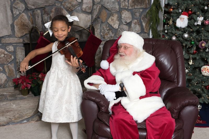 Six-year-old Abbie Winger plays “Silent Night” on the violin for Santa Phil during the Santa at the Studio event Dec. 3 at DayC Photography in Atlanta. CONTRIBUTED BY DAYC PHOTOGRAPHY 2017 WWW.DAYCPHOTOGRAPY.COM